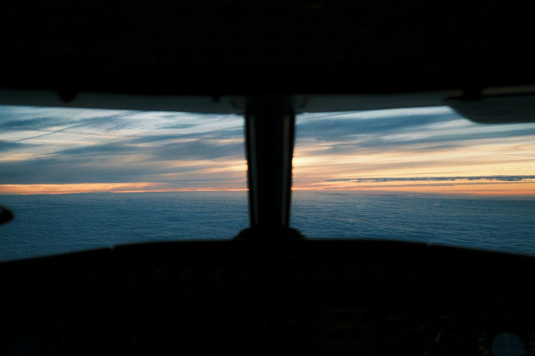 Blick aus einem Flugzeugcockpit auf eine dichte Wolkendecke im goldenen Abendlicht