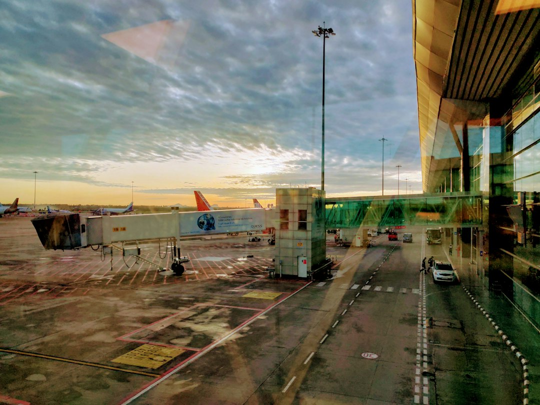 Flughafen bei Sonnenaufgang mit einer Fluggastbrücke, die das Terminal mit einem Flugzeug verbindet