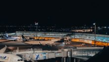 Flughafen bei Nacht mit beleuchteten Terminalgebäuden und Flugzeugen am Vorfeld
