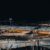 Flughafen bei Nacht mit beleuchteten Terminalgebäuden und Flugzeugen am Vorfeld