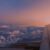 Blick aus einem Flugzeugfenster auf Wolken und den Horizont im Abendlicht