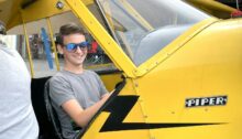 Mann sitzt im Cockpit eines gelben Kleinflugzeugs