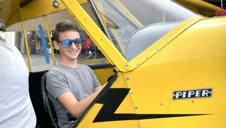 Mann sitzt im Cockpit eines gelben Kleinflugzeugs