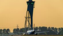 Verkehrsflugzeug auf dem Rollweg zur Startbahn, im Hintergrund ein Kontrollturm
