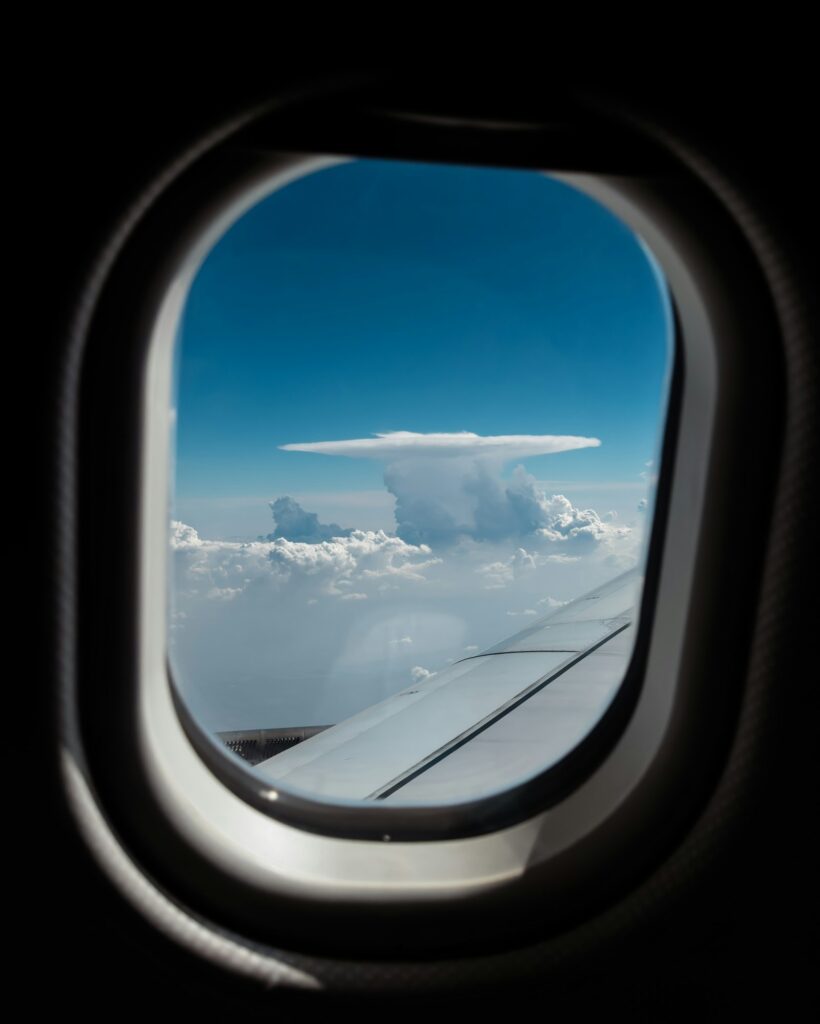 Blick aus einem Flugzeugfenster auf Wolken und blauen Himmel (Foto eines echten Flugs, kein Simulator-Bild)